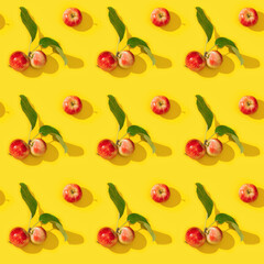 Seamless regular creative pattern from ripe small red apples and green leaves, food background.