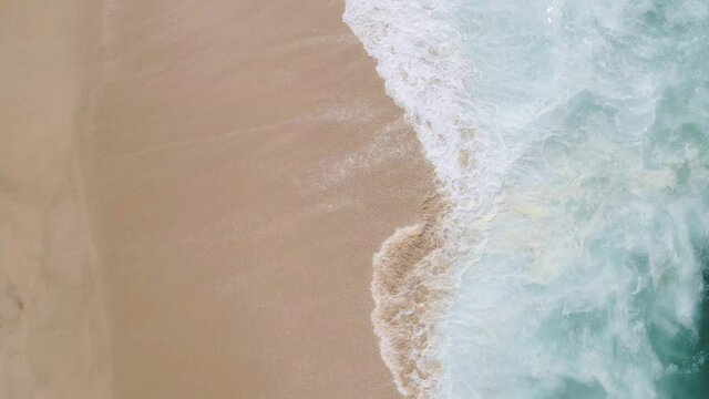 top view of a waves reaching the sand of the beach