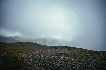 Dark atmospheric landscape on edge of abyss in highlands. Dangerous mountains and abyss among low...