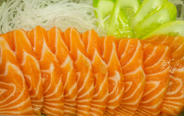 close up and select focus raw salmon slice or salmon sashimi in Japanese style , salmon sushi with fresh vegetables isolated on white background