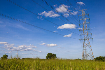 Landscape view of high voltage electric and electrical wires in the verdant meadow on deep blue sky...