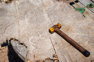 wood and rust head iron hammer lying on wooden board with outdoor workshop