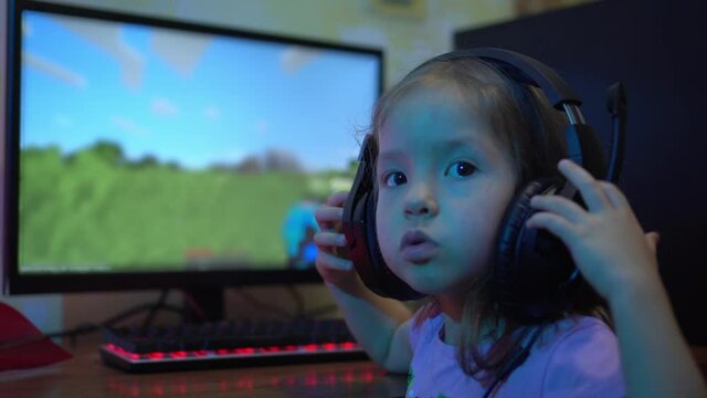 A child with headphones plays an online video game on the computer. The problem of Computer Game Addiction in Children