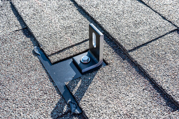 Residential asphalt shingle roof with metal anchors installed for the installation of a solar panel...