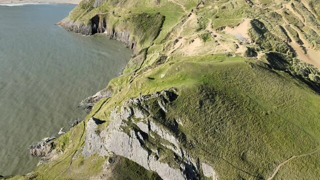 Aerial View Limestone Sea Cliffs Covered With Green Grass During Summer Near Three Cliffs Bay In Swansea, Wales.