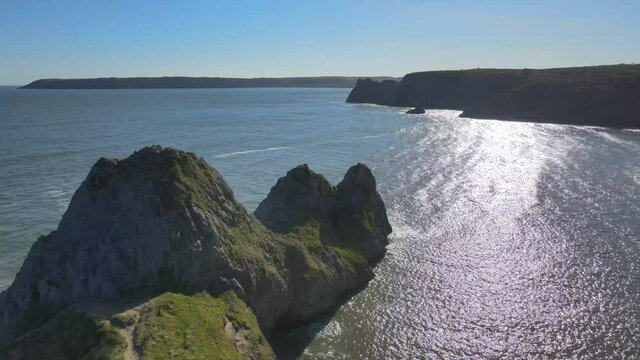 Bright Sunlight Reflecting On Calm Ocean From Three Cliffs Bay At Summer In Swansea, Wales, United Kingdom. - aerial