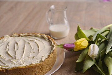 Banana homemade cake, a congratulatory bouquet of flowers and a jug of milk on the table.