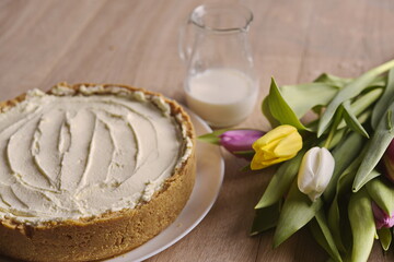 Banana homemade cake, a congratulatory bouquet of flowers and a jug of milk on the table.