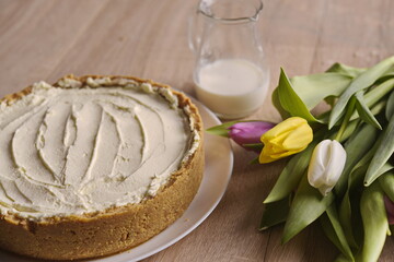 Banana homemade cake, a congratulatory bouquet of flowers and a jug of milk on the table.