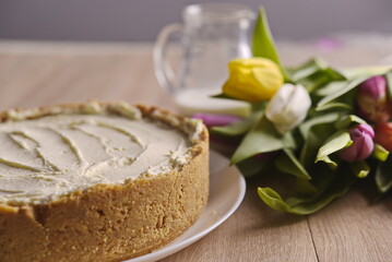 Banana homemade cake, a congratulatory bouquet of flowers and a jug of milk on the table.