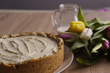 Banana homemade cake, a congratulatory bouquet of flowers and a jug of milk on the table.
