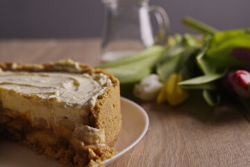 A piece of cake, a jug of milk, and a tulip are spread out on the table.