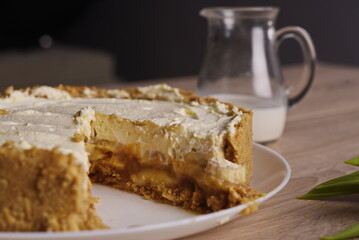 A piece of cake, a jug of milk, and a tulip are spread out on the table.