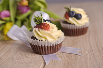 Cupcakes with berries and greeting flowers are laid out on the table.