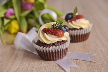 Cupcakes with berries and greeting flowers are laid out on the table.