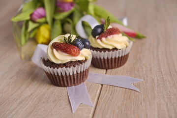 Cupcakes with berries and greeting flowers are laid out on the table.