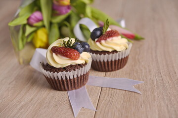 Cupcakes with berries and greeting flowers are laid out on the table.