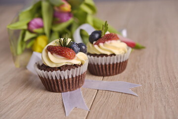 Cupcakes with berries and greeting flowers are laid out on the table.