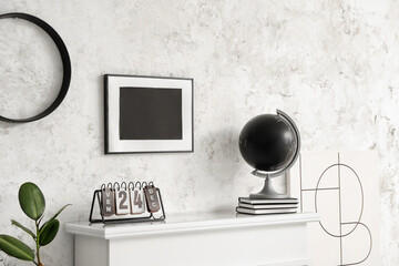 Calendar and globe on mantelpiece in room