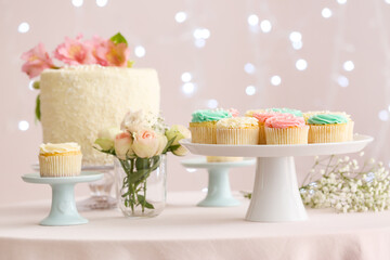 Tasty cupcakes and flowers on table prepared for party