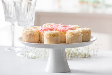 Dessert stand with tasty cupcakes on table