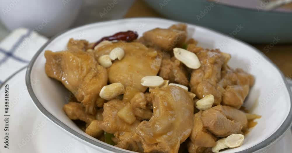 Wall mural sprinkling peanuts onto a bowl of homemade kung pao chicken close up