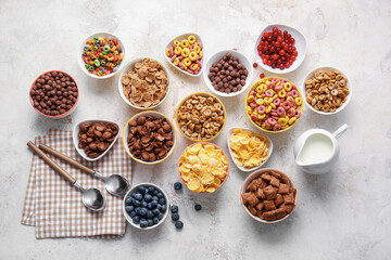 Bowls with different cereals and milk on light background