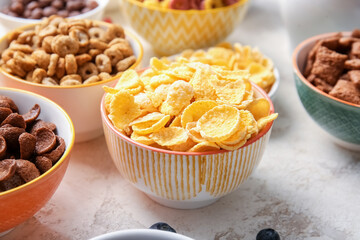Bowls with different cereals on light background, closeup