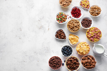 Bowls with different cereals and milk on light background