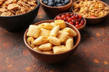 Bowls with different cereals and berries on grunge background, closeup