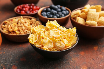 Bowls with different cereals and berries on grunge background, closeup