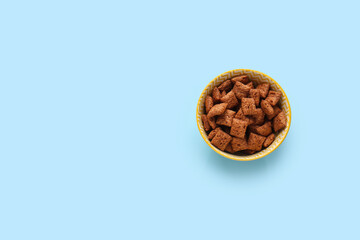 Bowl with tasty corn pillows on color background