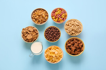 Bowls with different cereals and milk on color background
