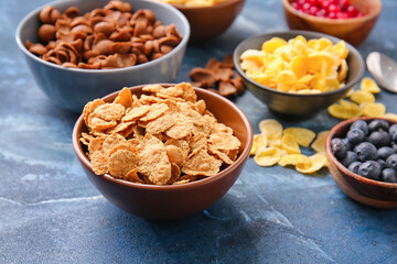 Bowls with different cereals and berries on color background, closeup