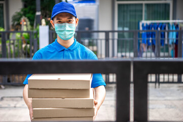 A young Asian deliveryman is delivering parcel to customer house ordered online during the outbreak...
