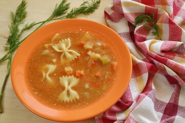 tomato soup in a bowl, decorated with linen kitchen cloth and green herbs