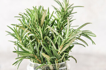 Jar with fresh rosemary on light background, closeup