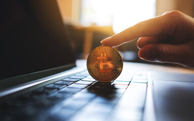 People holding and showing bitcoin on laptop computer