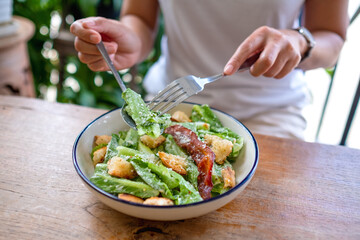 Closeup image of a woman eating a Caesar salad