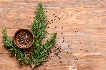 Fresh rosemary and peppercorns on wooden background