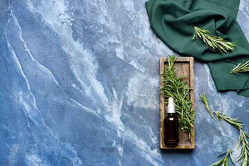 Bottle of essential oil and fresh rosemary on color background