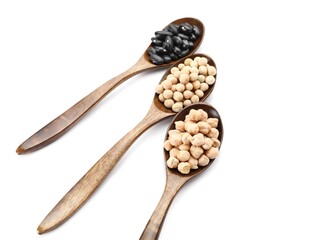 Spoons with different legumes on white background