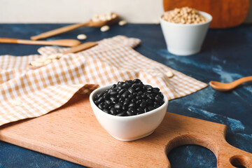 Bowl with black beans on color background