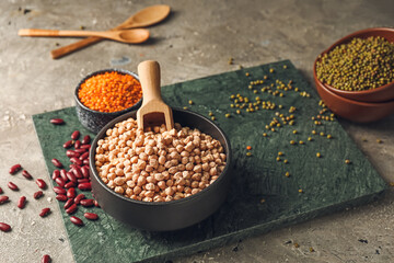 Bowls with different legumes on grey background