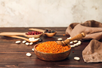 Bowl and spoons with different legumes on table