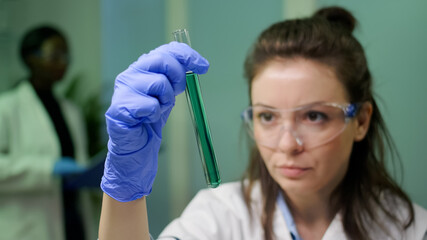 Closeup of scientist woman looking at test tube with dna sample examining for microbiology...