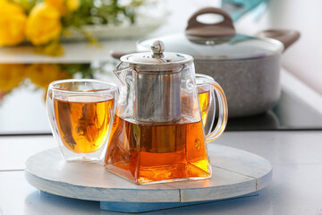 Teapot and cup of hot beverage on table in room