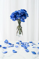 Vase with beautiful blue roses on table against light background