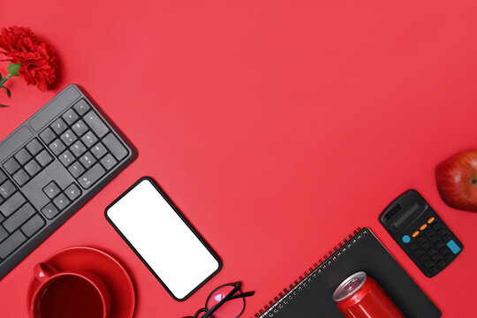 Mock up mobile phone, notebook, red can, calculator, coffee cup and apple on red background. Copy space.