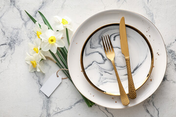 Beautiful table setting with narcissus flowers on light background